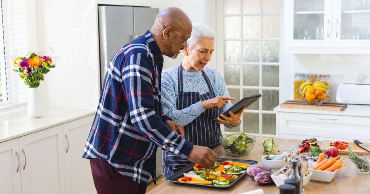 senior couple preparing meal using tablet in kitchen
