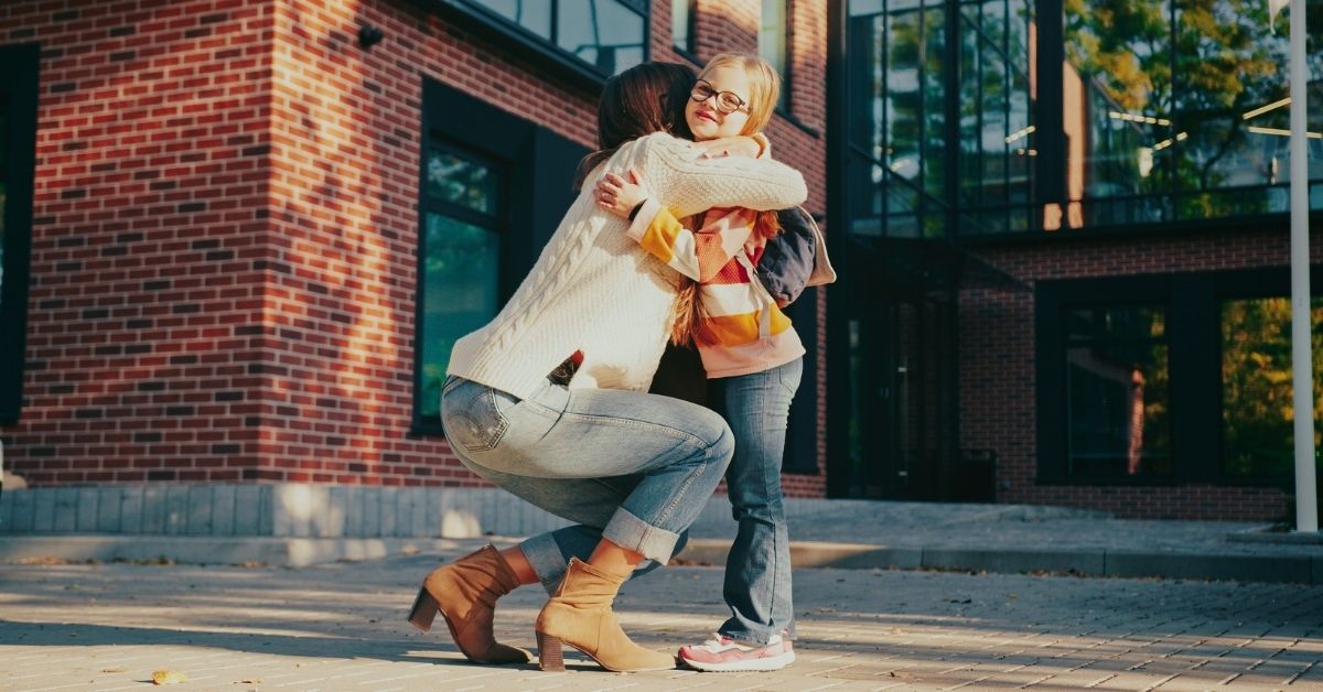 A mom kneels at eye level with her daughter, offering calm connection and emotional support during a parenting power struggle.