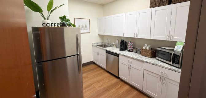 Clean office kitchen with coffee bar, stainless steel refrigerator, dishwasher, and microwave