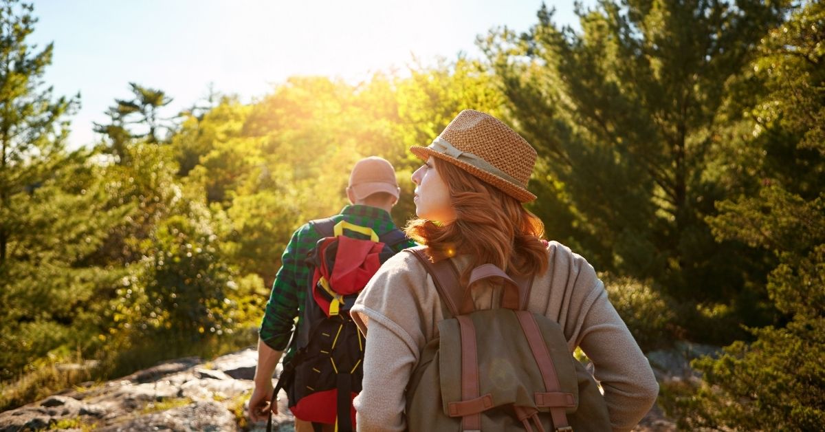 young couple hiking in the afternoon, surrounded by evergreen trees